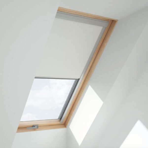 A beige RoofLITE+ blackout blind partially lowered on a pine wood roof window installed in a white ceiling.