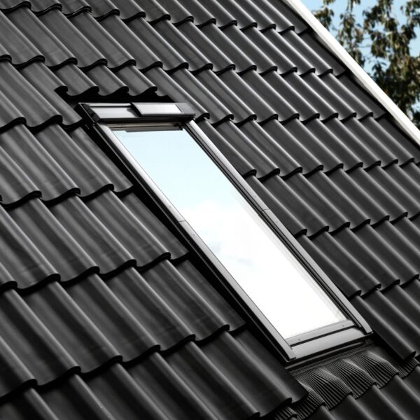 VELUX roof window upgraded with a Solar Conversion Kit, showing the integrated slim solar panel on the exterior frame against black roof tiles.